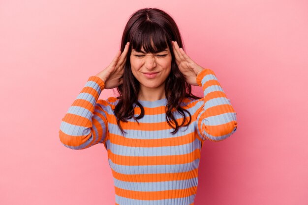 Young caucasian woman isolated on pink background having a head ache, touching front of the face.