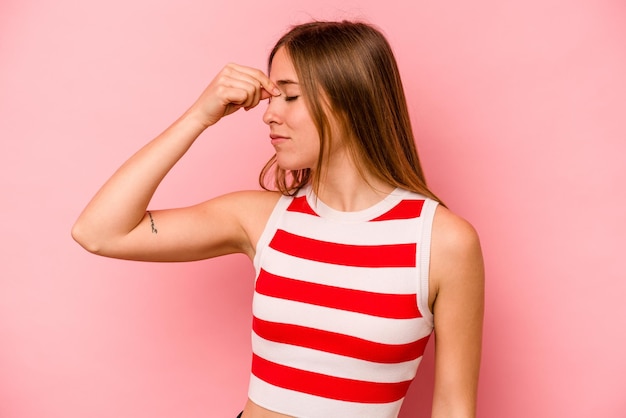 Young caucasian woman isolated on pink background having a head ache touching front of the face