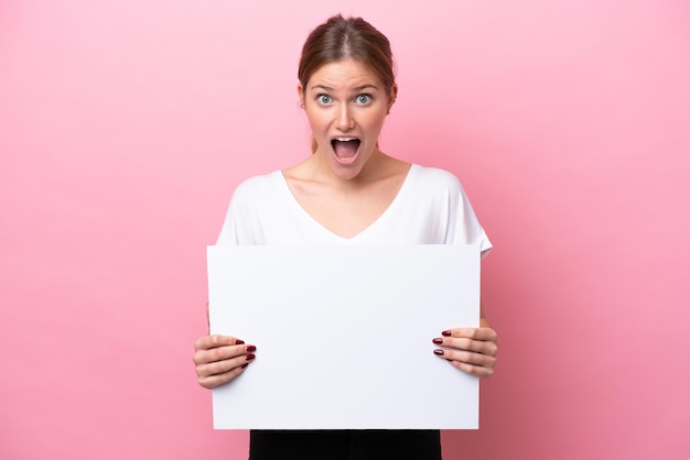 Young caucasian woman isolated on pink background holding an empty placard with happy expression