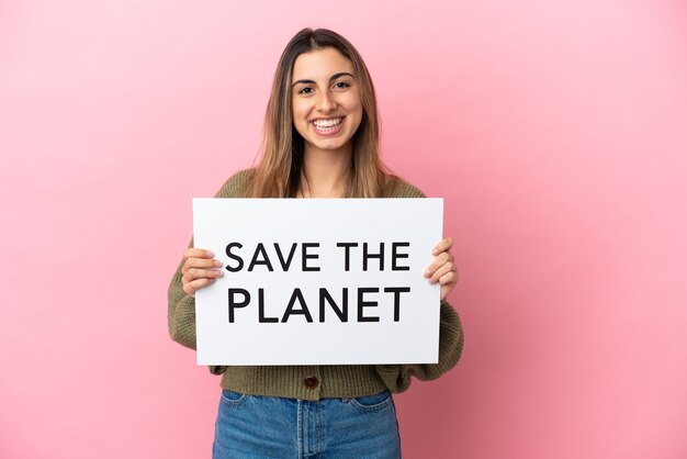 Young caucasian woman isolated on pink background holding a placard with text Save the Planet with happy expression