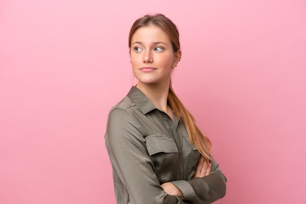 Photo young caucasian woman isolated on pink background looking to the side