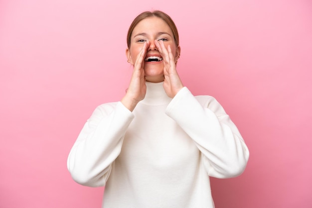 Young caucasian woman isolated on pink background shouting and announcing something