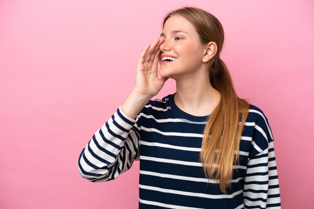 Young caucasian woman isolated on pink background shouting with mouth wide open to the side