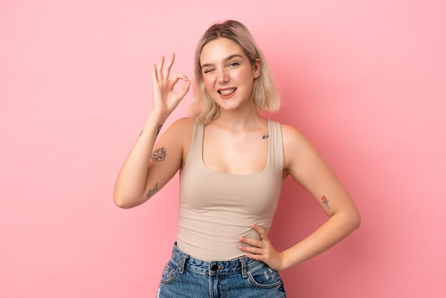 Young caucasian woman isolated on pink background showing ok sign with fingers