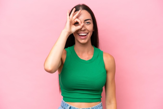 Young caucasian woman isolated on pink background showing ok sign with fingers