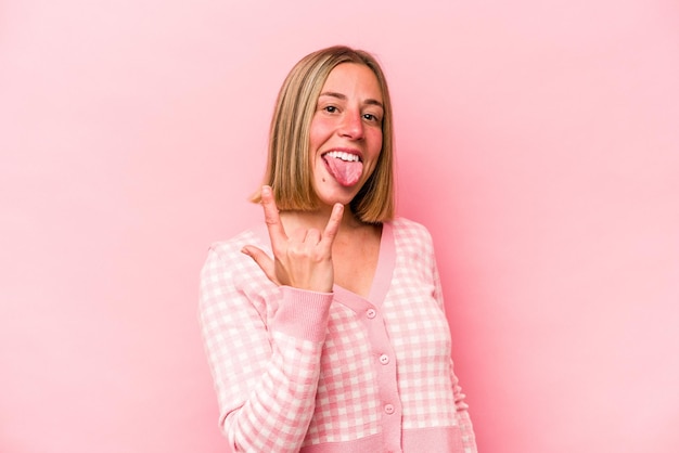 Young caucasian woman isolated on pink background showing rock gesture with fingers