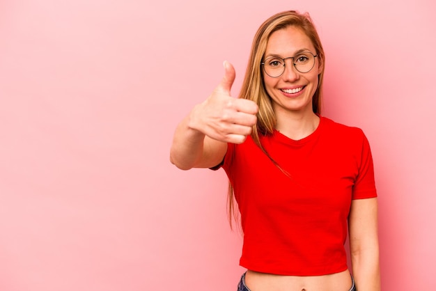 Photo young caucasian woman isolated on pink background smiling and raising thumb up