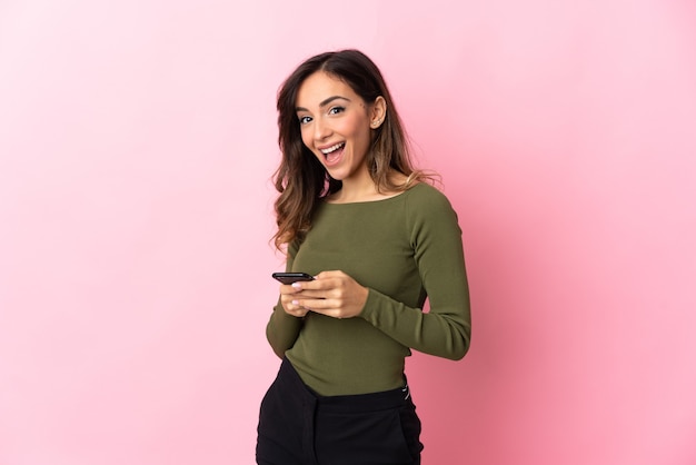 Young caucasian woman isolated on pink background surprised and sending a message