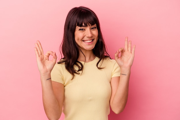 Young caucasian woman isolated on pink wall cheerful and confident showing ok gesture.