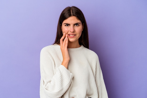 Young caucasian woman isolated on purple background having a strong teeth pain, molar ache.