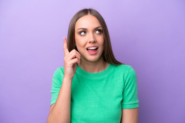 Young caucasian woman isolated on purple background intending to realizes the solution while lifting a finger up