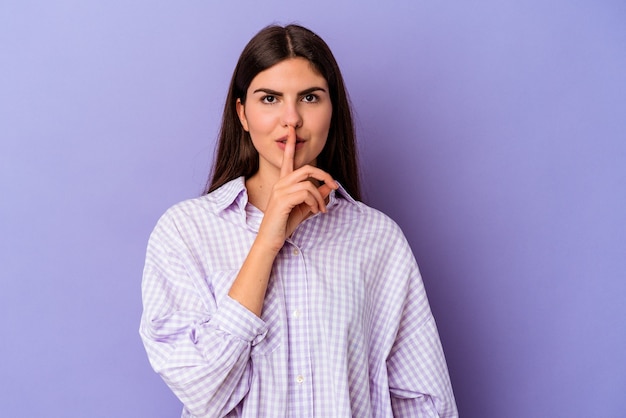 Young caucasian woman isolated on purple background keeping a secret or asking for silence.