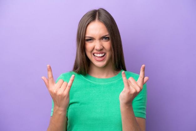 Young caucasian woman isolated on purple background making horn gesture