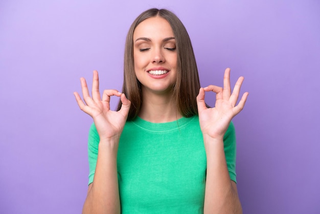 Young caucasian woman isolated on purple background in zen pose