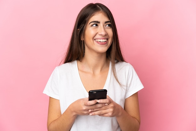 Young caucasian woman isolated using mobile phone and looking up