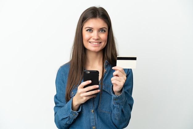 Young caucasian woman isolated on white background buying with the mobile with a credit card