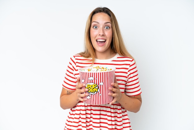 Young caucasian woman isolated on white background holding a big bucket of popcorns