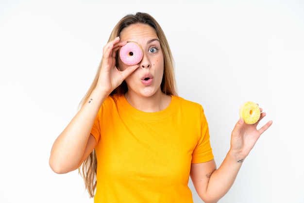 Young caucasian woman isolated on white background holding a donut in an eye