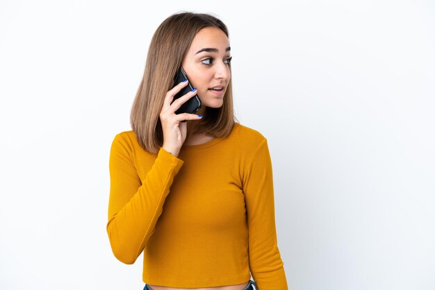 Young caucasian woman isolated on white background keeping a conversation with the mobile phone with someone