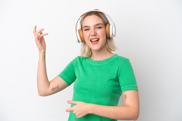 Young caucasian woman isolated on white background listening music and doing guitar gesture