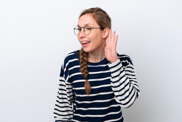 Young caucasian woman isolated on white background listening to something by putting hand on the ear