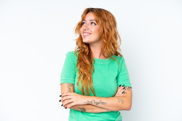 Young caucasian woman isolated on white background looking up while smiling