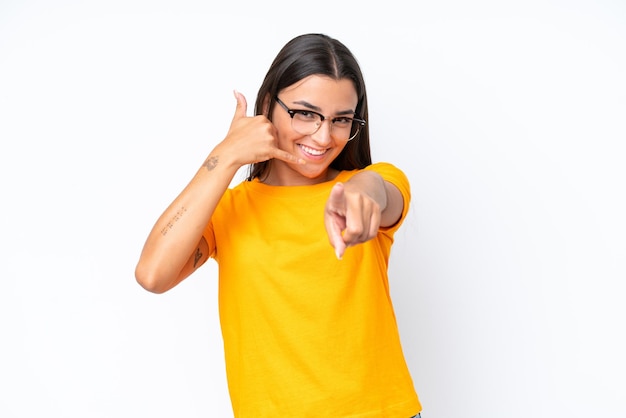 Young caucasian woman isolated on white background making phone gesture and pointing front