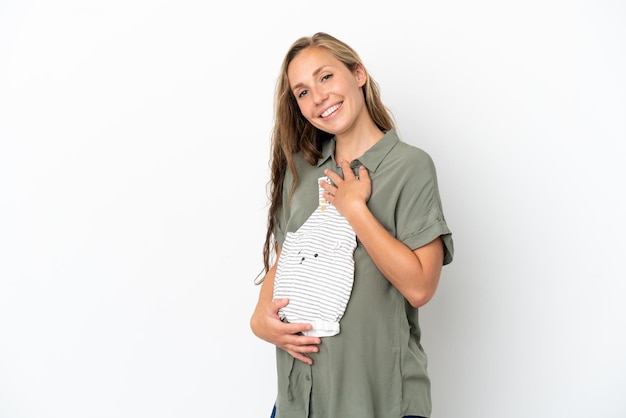 Young caucasian woman isolated on white background pregnant and holding baby clothes