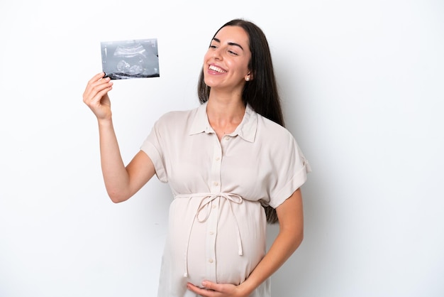 Young caucasian woman isolated on white background pregnant and holding an ultrasound