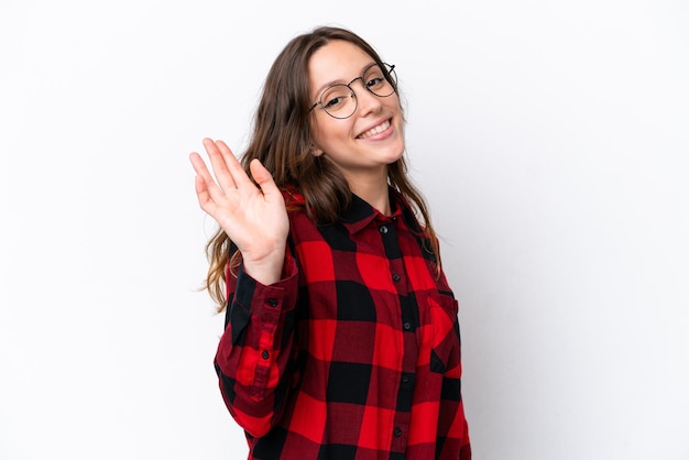 Young caucasian woman isolated on white background saluting with hand with happy expression