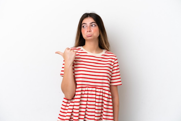 Young caucasian woman isolated on white background unhappy and pointing to the side