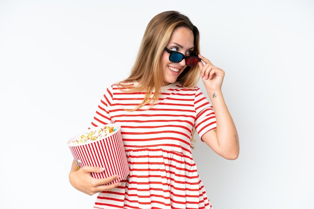 Young caucasian woman isolated on white background with 3d glasses and holding a big bucket of popcorns