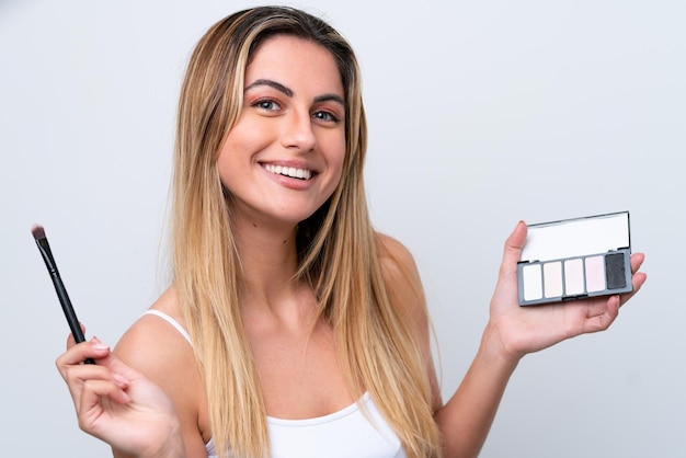 Young caucasian woman isolated on white background with makeup palette and happy