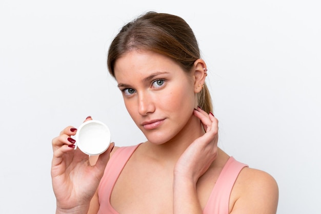 Young caucasian woman isolated on white background with moisturizer