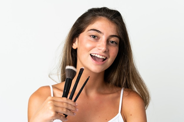 Young caucasian woman isolated on white holding makeup brush