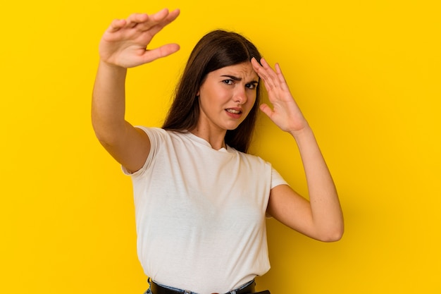 Young caucasian woman isolated on yellow background being shocked due to an imminent danger