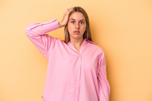 Young caucasian woman isolated on yellow background being shocked, she has remembered important meeting.