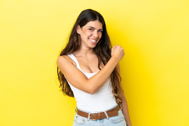 Young caucasian woman isolated on yellow background celebrating a victory