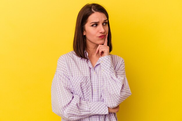 Young caucasian woman isolated on yellow background contemplating planning a strategy thinking about the way of a business