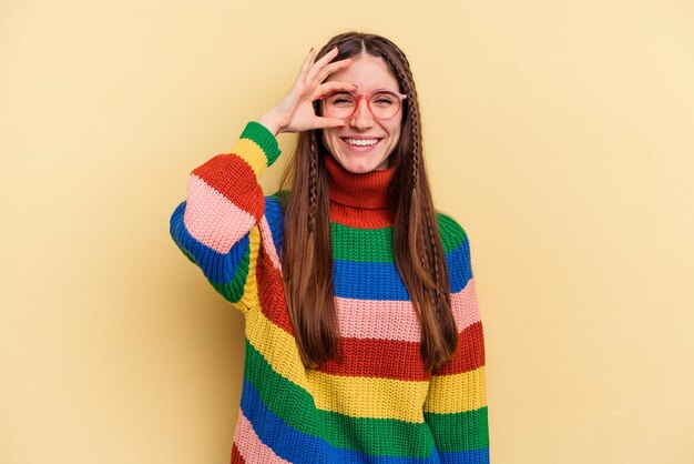 Young caucasian woman isolated on yellow background excited keeping ok gesture on eye.