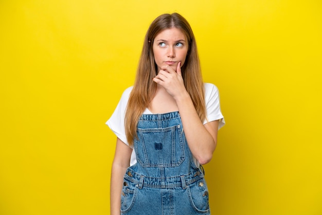 Young caucasian woman isolated on yellow background having doubts and with confuse face expression