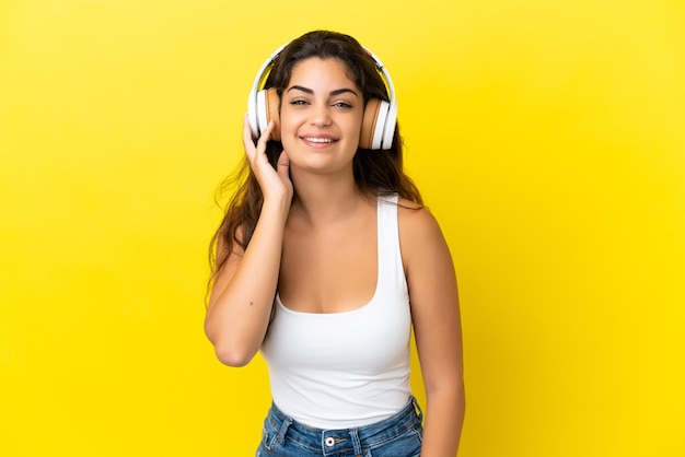 Young caucasian woman isolated on yellow background listening music