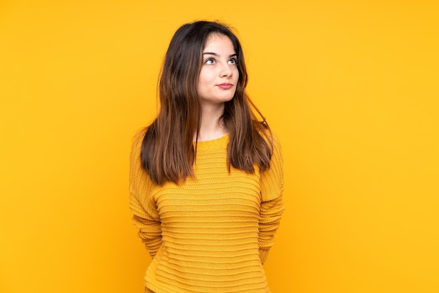 Photo young caucasian woman isolated on yellow background and looking up