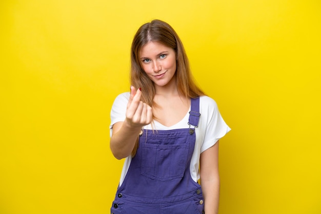 Young caucasian woman isolated on yellow background making money gesture