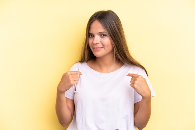 Young caucasian woman isolated on yellow background pointing to oneself