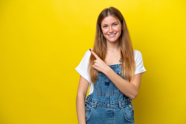 Young caucasian woman isolated on yellow background pointing to the side to present a product