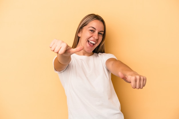 Young caucasian woman isolated on yellow background raising both thumbs up, smiling and confident.