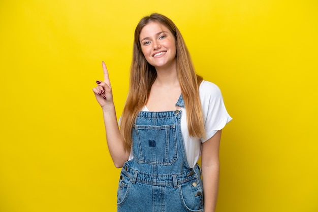 Young caucasian woman isolated on yellow background showing and lifting a finger in sign of the best