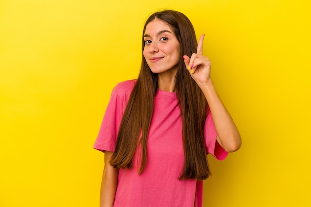 Young caucasian woman isolated on yellow background showing number one with finger.