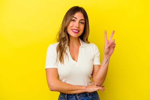 Young caucasian woman isolated on yellow background showing number two with fingers.